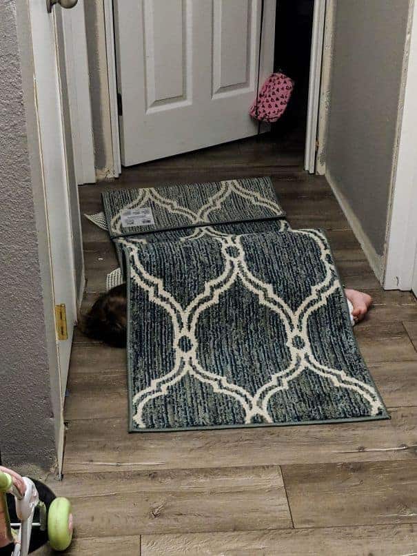 Menina se escondendo embaixo do tapete para não dormir