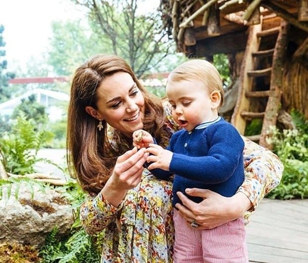 Kate Middleton com o príncipe Louis em um jardim