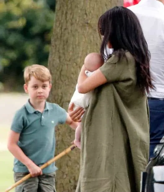 príncipe George, primogênito de Kate Middleton, olhando para Archie no colo de Meghan Markle