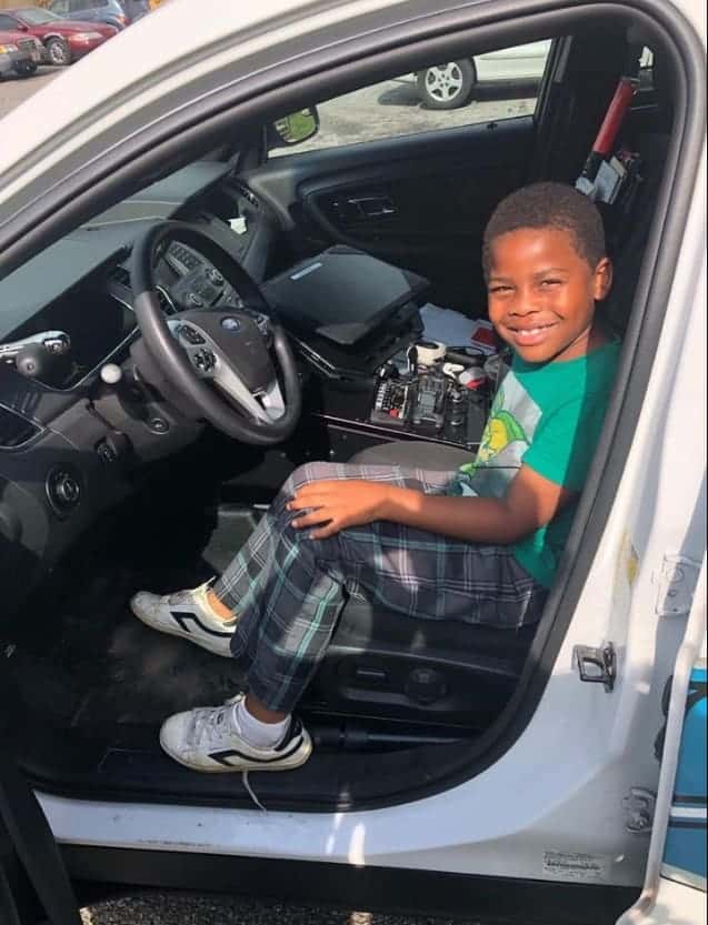 O menino pode até tirar foto no carro da polícia 