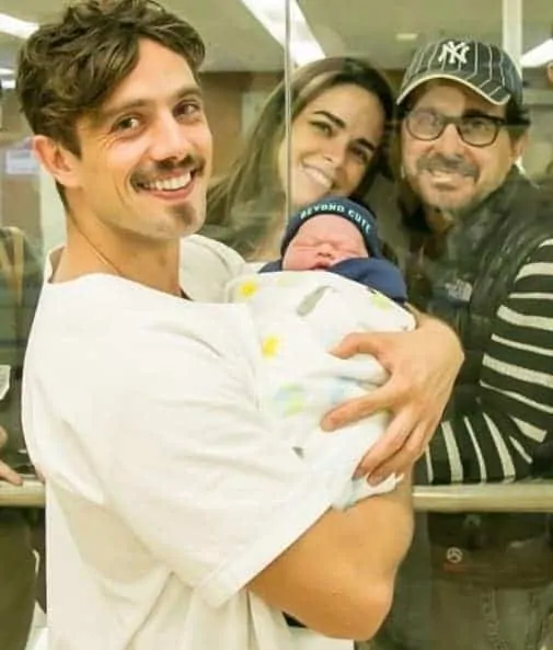 O ator Rafael Cardoso com o pequeno Valentim no colo e o vovô no fundo, o diretor Edson Spinello