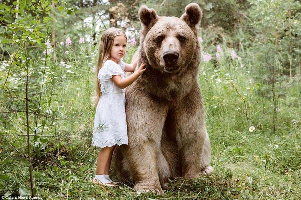 As crianças brincam na flores com o urso Stepan de 300 kilos
