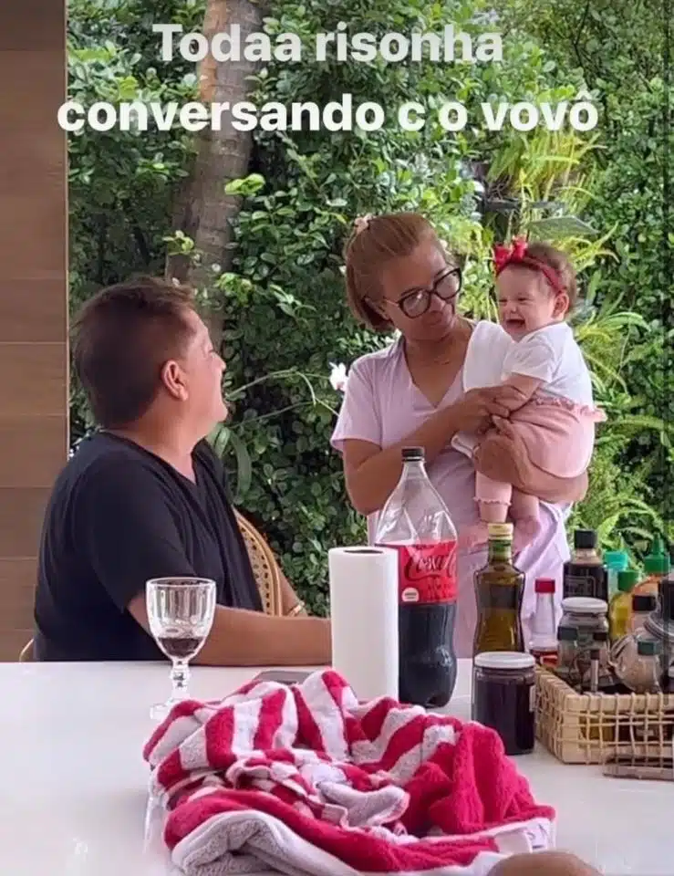 Leonardo posa com a neta de três meses e a babá dela em sua mansão