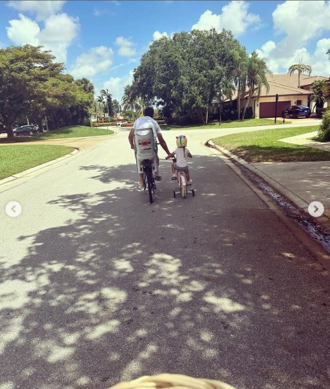 Filha caçula de Claudia Leitte posa com pai andando de bicicleta no seu condomínio nos EUA e impressiona