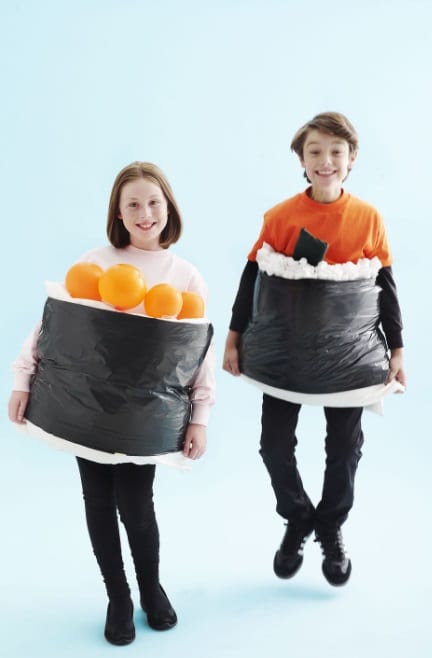 A fantasia de sushi é inovadora e pode ser feita com um saco de lixo preto, toalhas brancas e balões laranjas