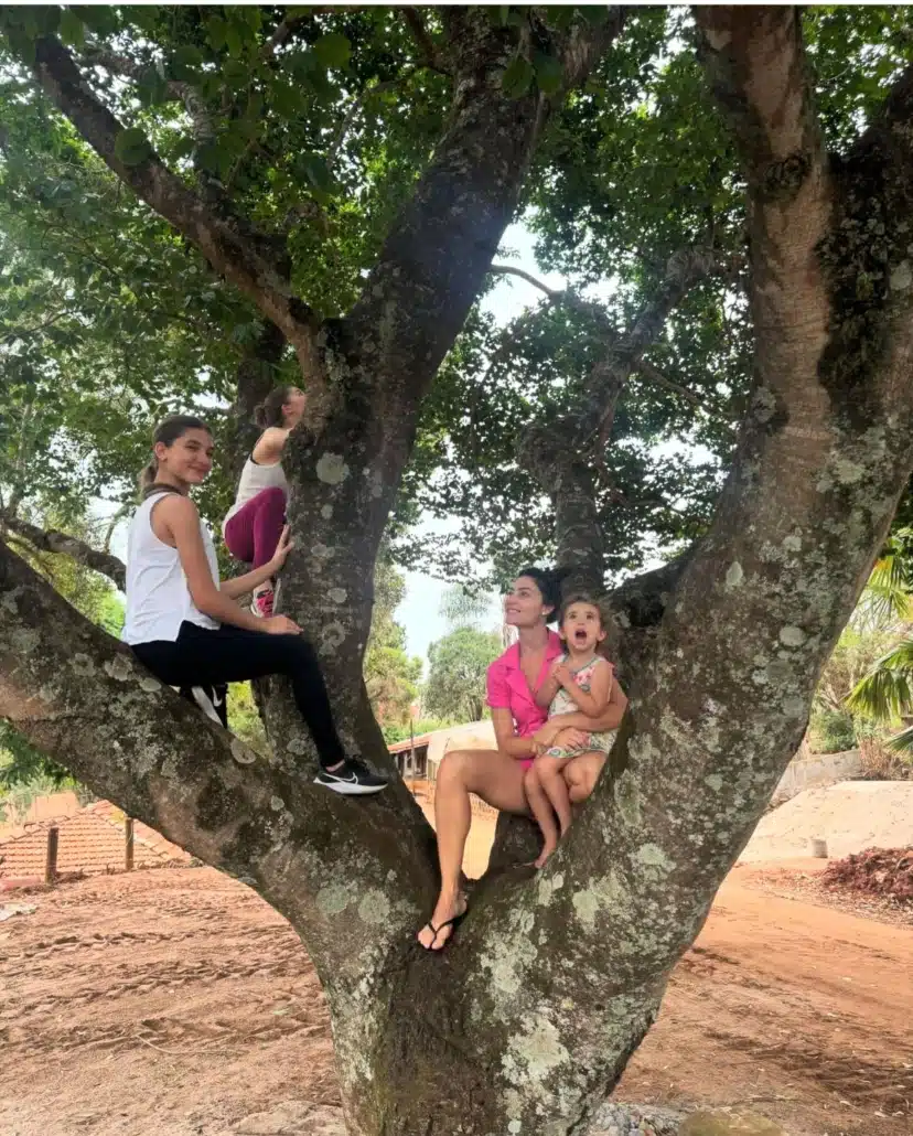 Filhas de Daniel posam com a mãe em cima de uma árvore