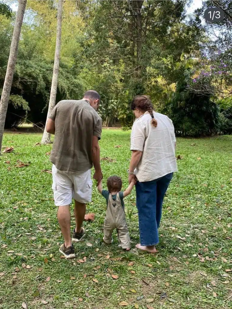 Damião andando de mãos dadas com os pais, Leandra Leal e Guilherme Burgos