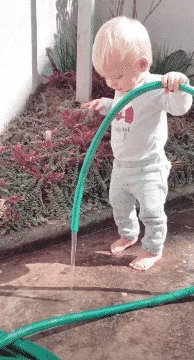 O filho de Karina Bacchi, o pequeno Enrico brincando com mangueira d’água