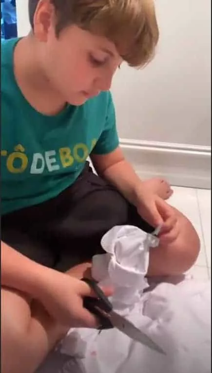Filho de Claudia Leitte cortando etiquetas das roupinhas de Bela