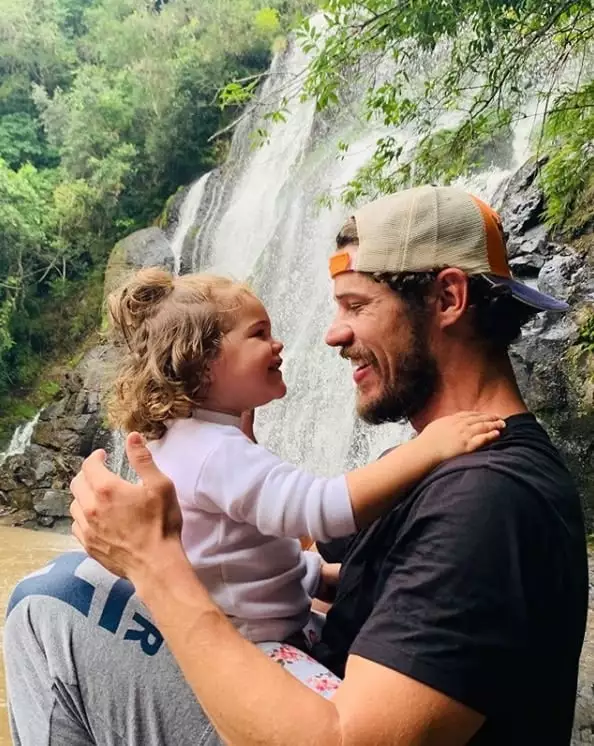 José Loreto com sua bebê diante da cachoeira
