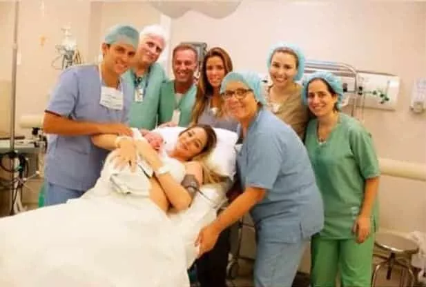 Imagem de Luma Costa com seu filho recém-nascido com a equipe médica