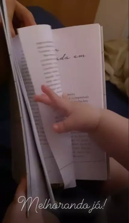 Bebê de Paulo Gustavo com um livro em registro feito pelo pai Thales Bretas