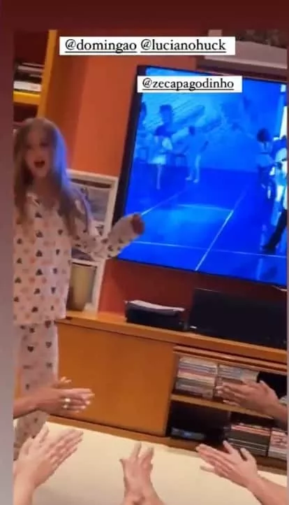 Angélica mostrando a filha na sua sala de televisão gigante