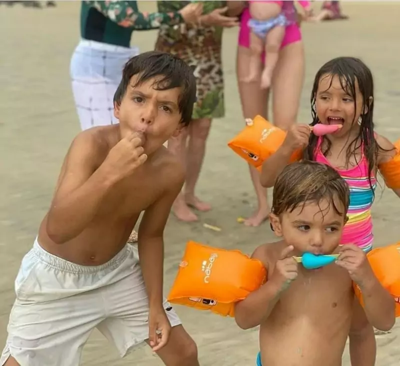 Filhos de Patrícia Abravanel surgem comendo picolé na praia e surpreendem