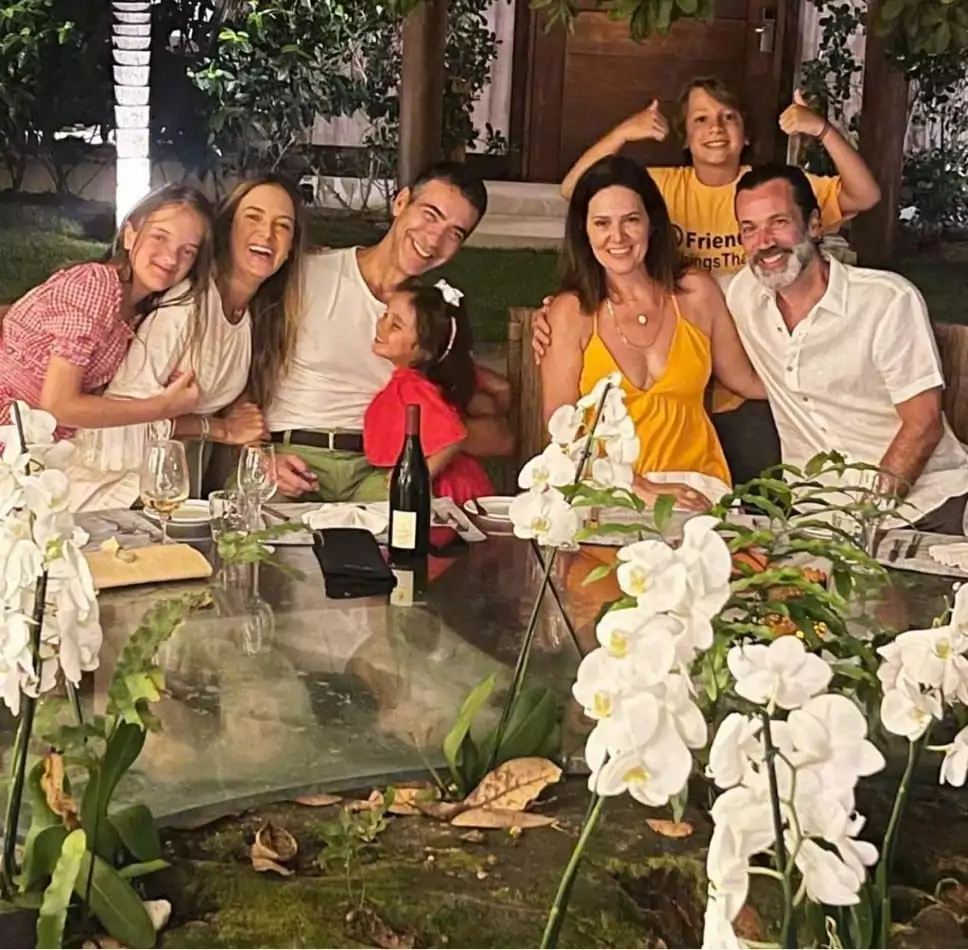 Tici e César Tralli com a família reunida em um jantar, na viagem 