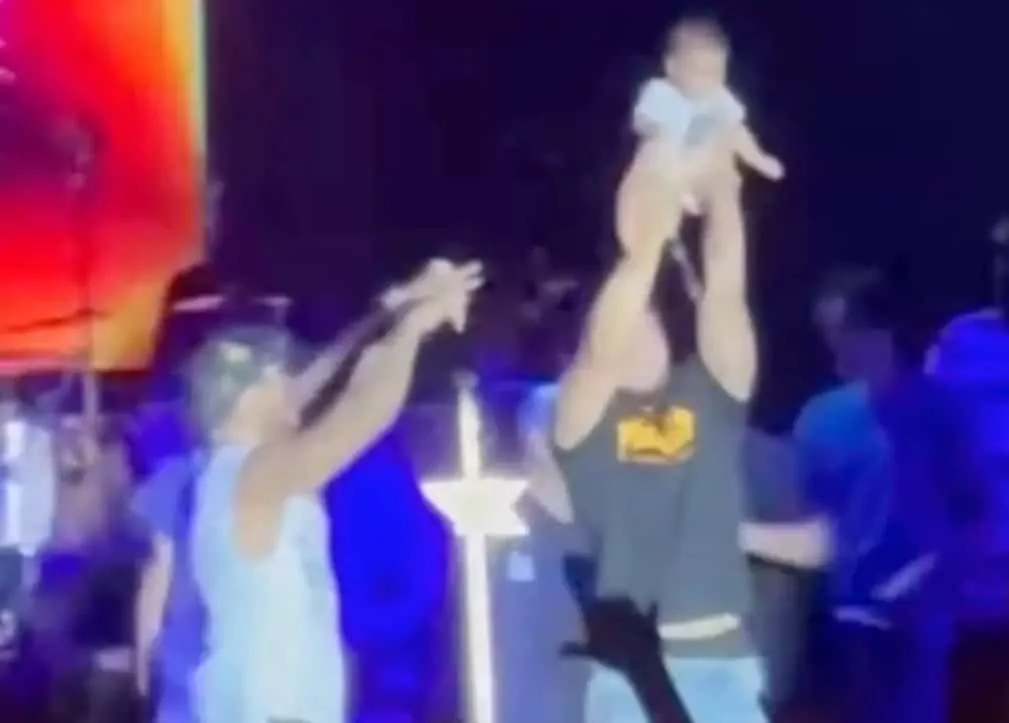 Bebê no palco acompanhado da equipe do cantor